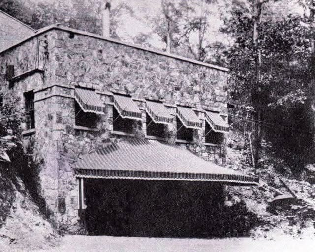 Period photograph of the stone entrance building and foyer built over Bangor Cave's nightclub entrance, with striped awnings over the window openings