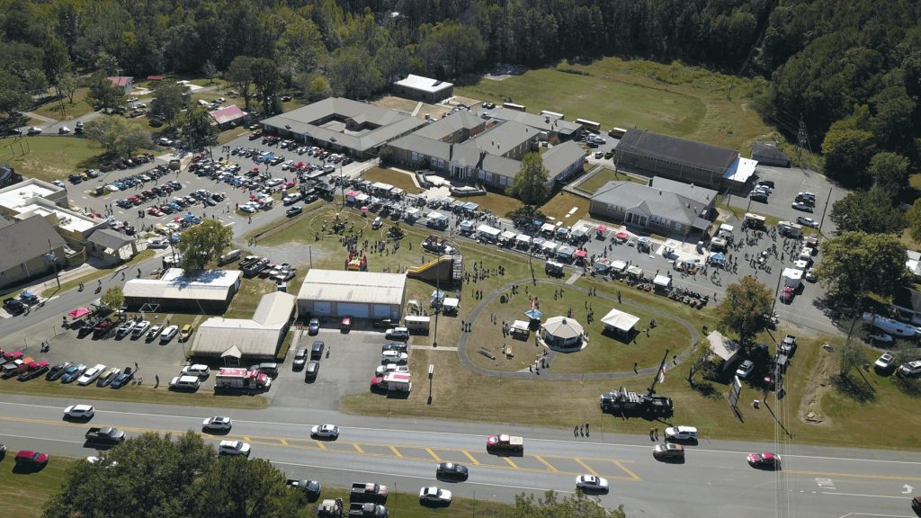 Aerial view of a Hayden Day crowd, vendor tents, rides, and classic cars around the Hayden town hall park